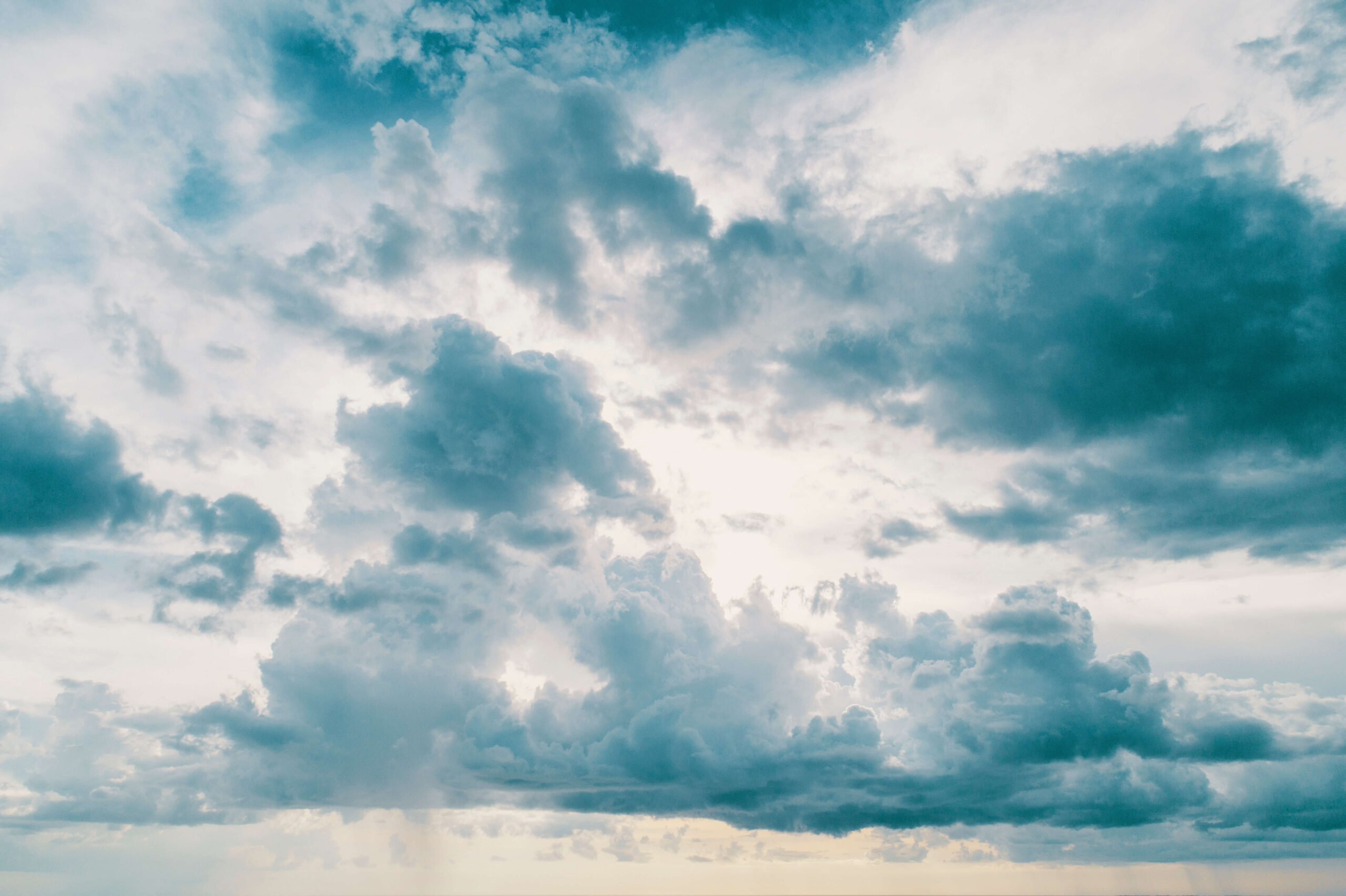 Dramatic cloudy sky with soft sunlight peeking through, creating a serene and peaceful atmosphere.