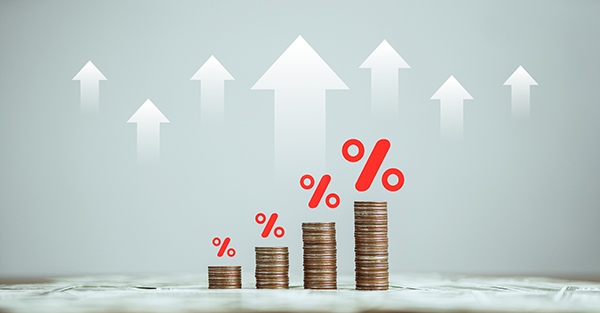 Stacked coins with percentage symbols and upward arrows, representing economic growth and increasing rates.