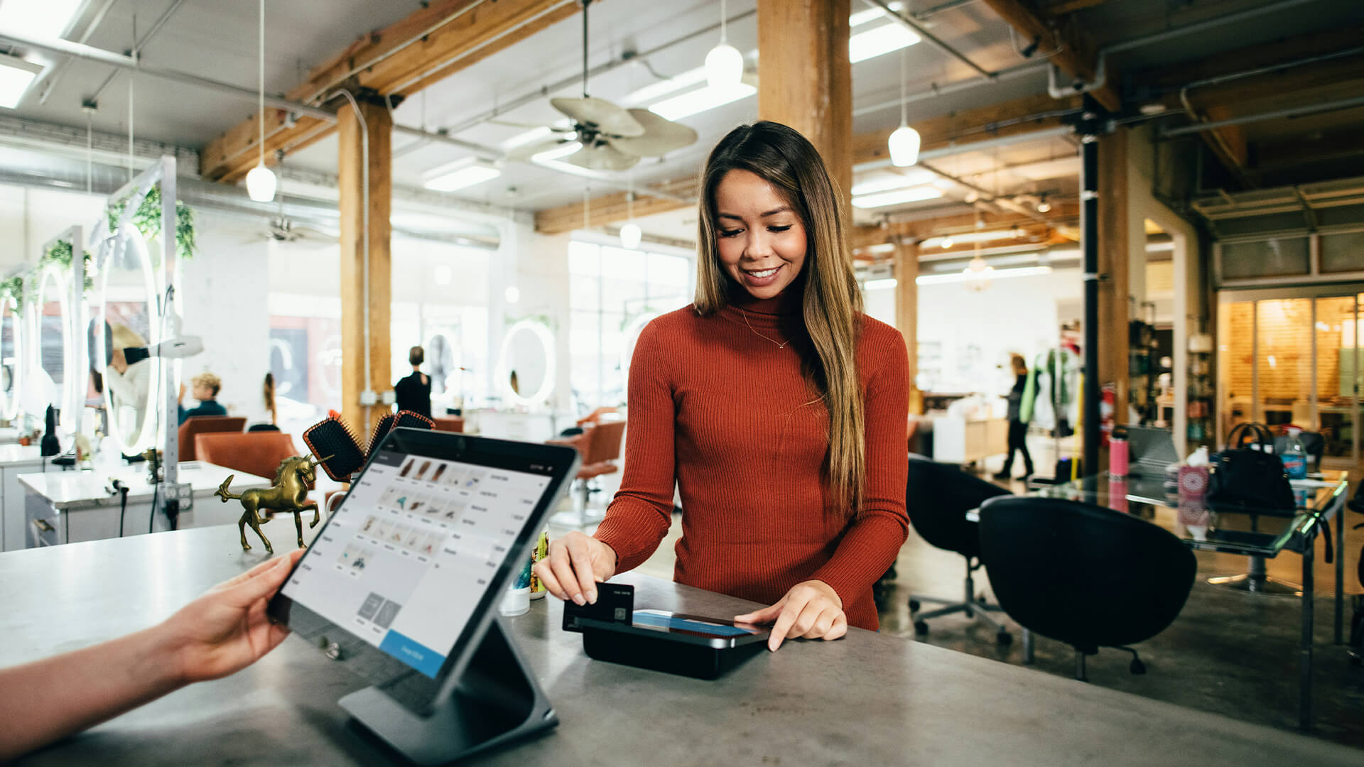 Woman paying at cafe counter with credit card in cozy, modern setting.